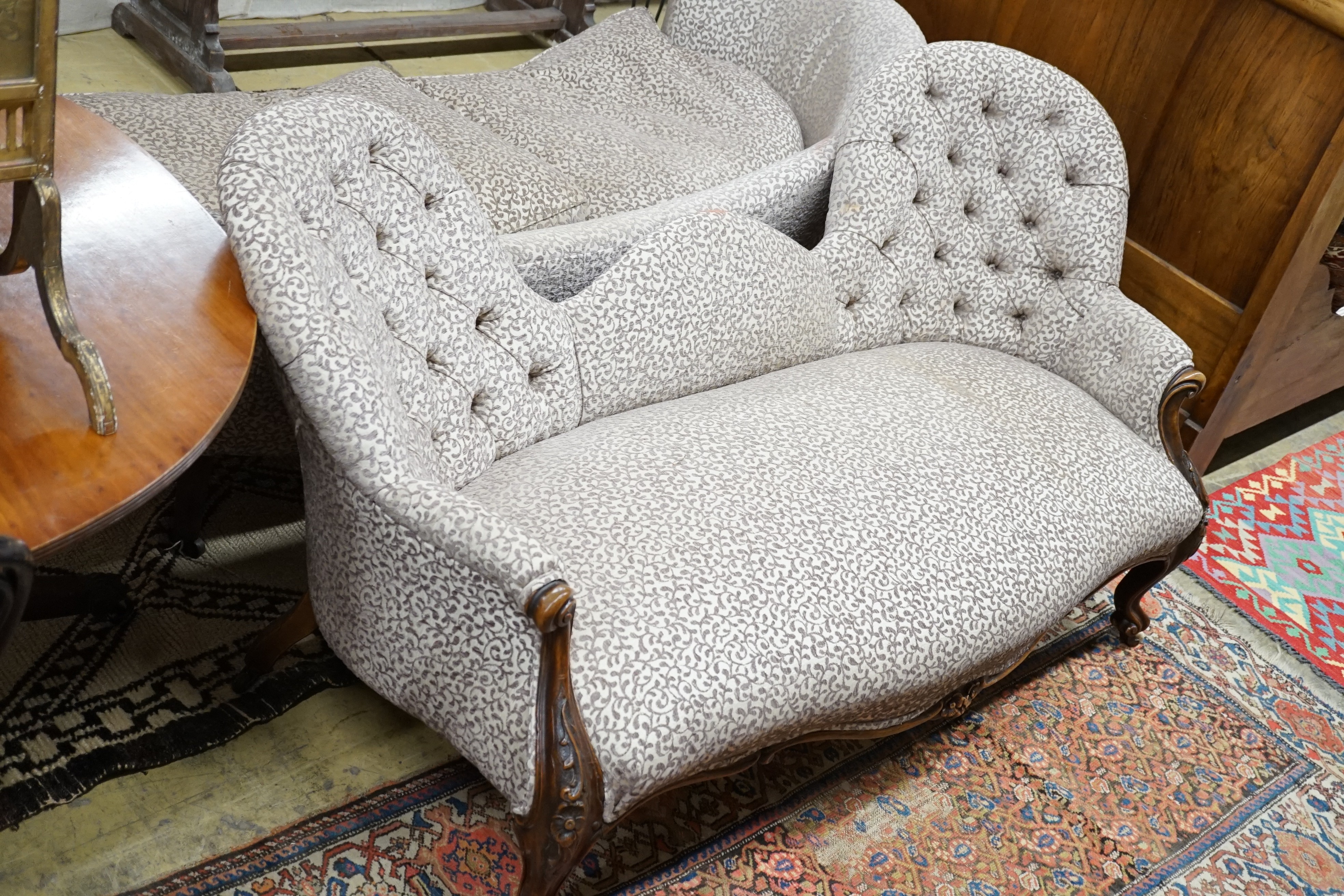 A Victorian and later walnut button back upholstered salon settee, with cabriole legs fitted ceramic castors, length 174cm